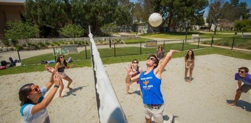 Student play beach volleyball on campus